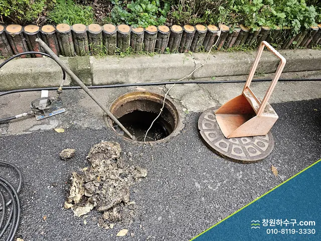 맨홀에서 퍼낸 오물 더미와 열린 맨홀