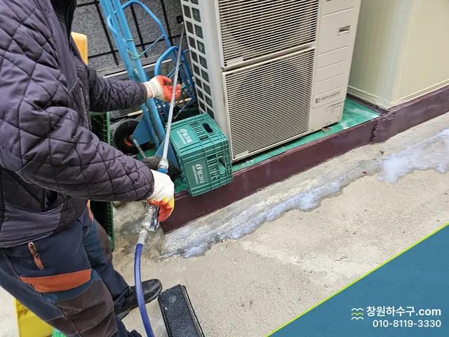 실외기 옆에서 호스로 배관을 세척하는 중