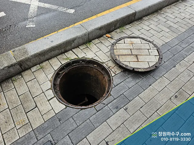보도에서 뚜껑을 연 원형 맨홀